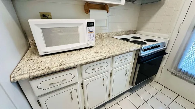 a kitchen with granite countertop white cabinets and white appliances