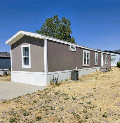 1604 180 East Tooele, UT 84074 - Photo 3 of 16 Single-level residence featuring a gray siding exterior, white trim, and a white perimeter skirting