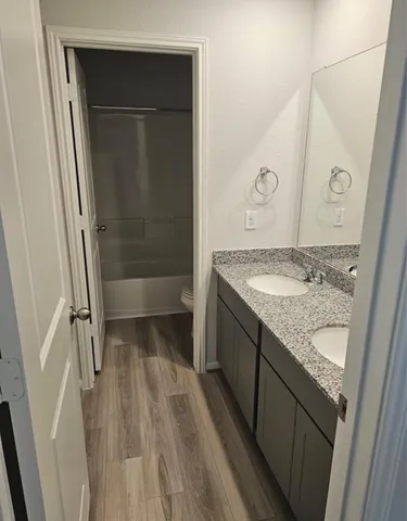 a bathroom with a granite countertop sink a toilet and shower