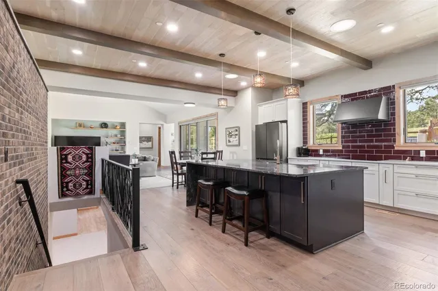 a kitchen with stainless steel appliances granite countertop a table chairs sink refrigerator and cabinets