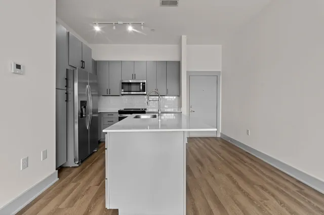 a kitchen with a refrigerator a sink and wooden floor
