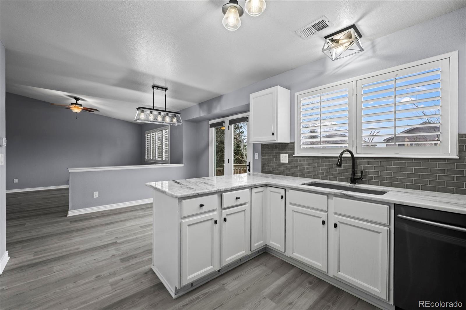 9664 Whitecliff Place Highlands Ranch, CO 80129 - Photo 12 of 46 a kitchen with a sink dishwasher a stove and white cabinets with wooden floor
