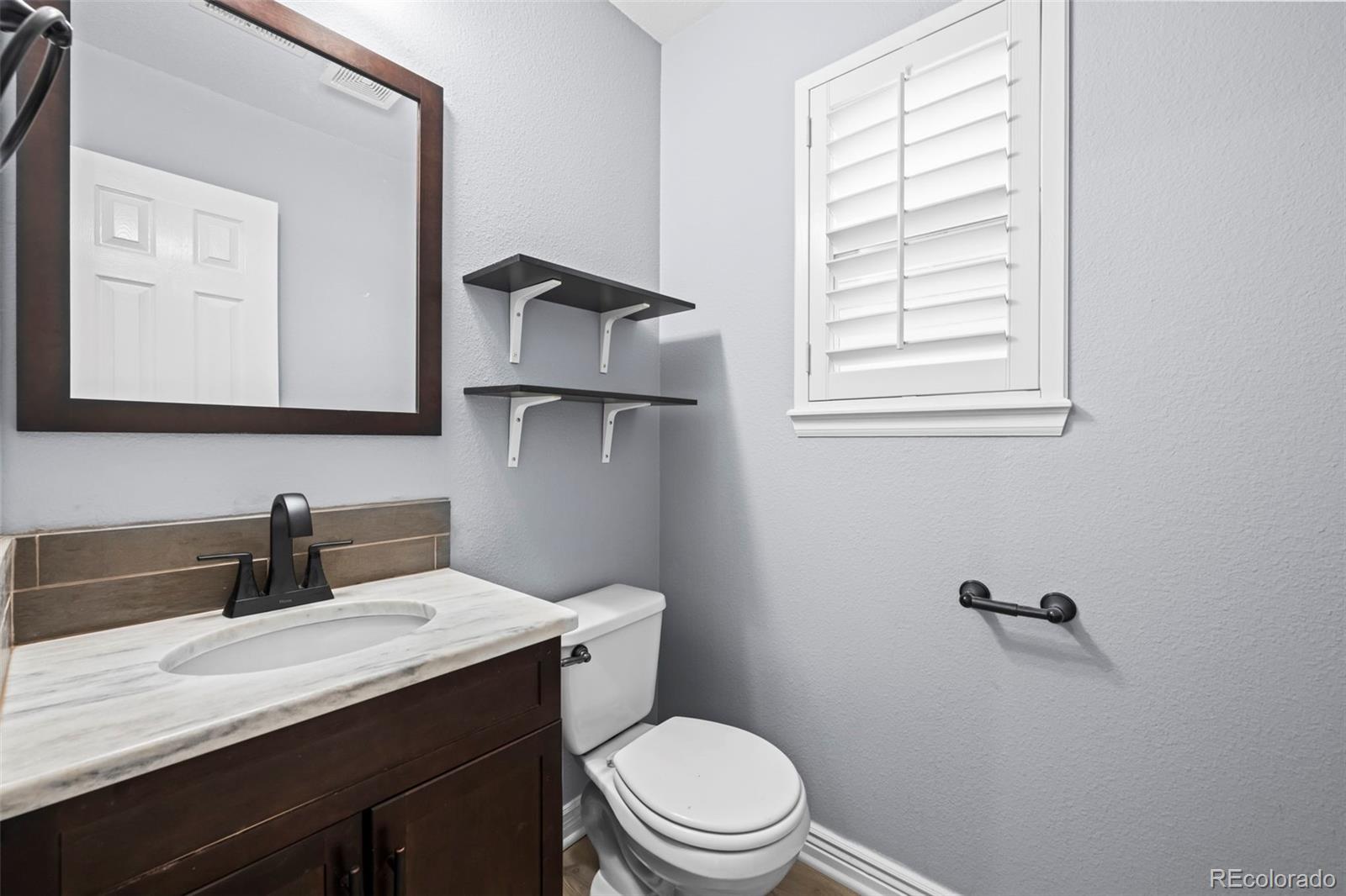 9664 Whitecliff Place Highlands Ranch, CO 80129 - Photo 13 of 46 a bathroom with a granite countertop sink toilet a mirror and shower