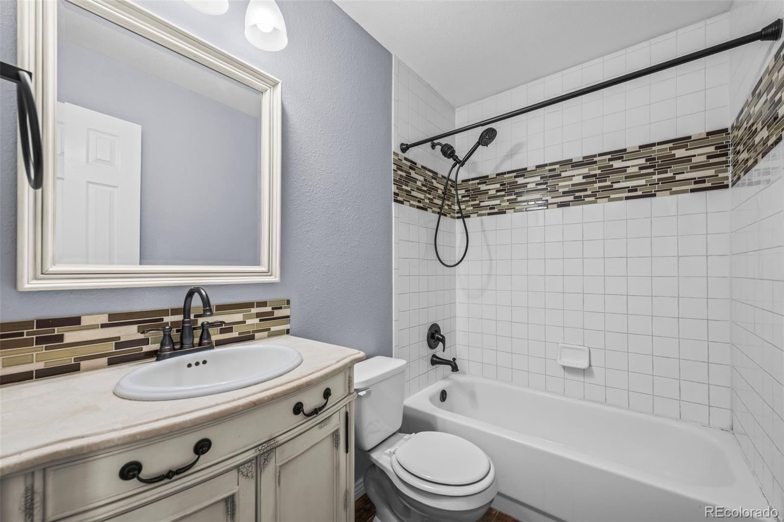 9664 Whitecliff Place Highlands Ranch, CO 80129 - Photo 13 of 38 a bathroom with a sink a toilet a mirror a bathtub and shower