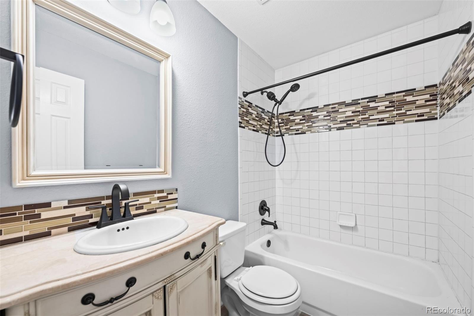 9664 Whitecliff Place Highlands Ranch, CO 80129 - Photo 18 of 46 a bathroom with a sink a toilet a mirror a bathtub and shower