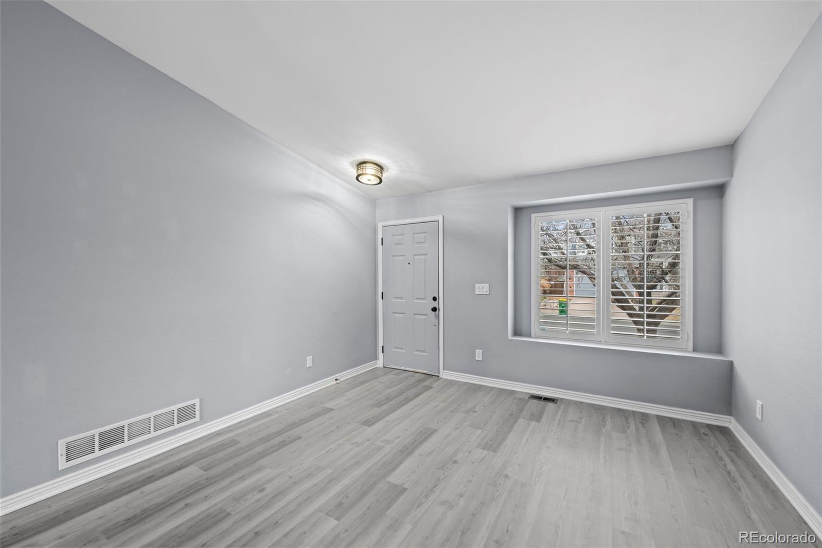 9664 Whitecliff Place Highlands Ranch, CO 80129 - Photo 3 of 46 a view of an empty room with a window and wooden floor