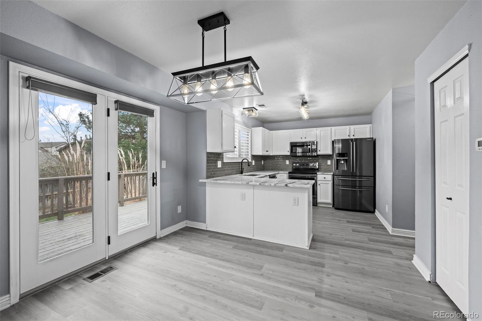 9664 Whitecliff Place Highlands Ranch, CO 80129 - Photo 9 of 46 a kitchen with stainless steel appliances granite countertop a refrigerator a sink dishwasher a stove and white cabinets with wooden floor
