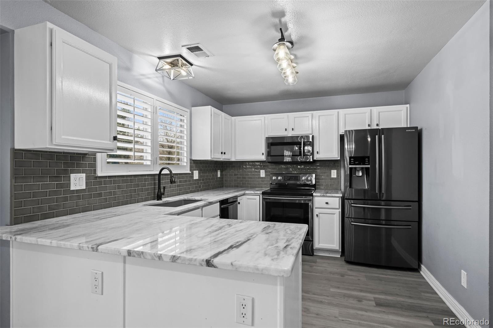 9664 Whitecliff Place Highlands Ranch, CO 80129 - Photo 10 of 46 a kitchen with kitchen island granite countertop a refrigerator stove and sink