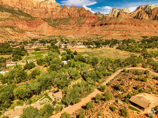 1219 Canyon Springs Road, Unit 34 Springdale, UT 84767 - Photo 16 of 17 Expansive property with a detached residence featuring a brown shingle roof, surrounded by natural desert landscaping and mature trees
