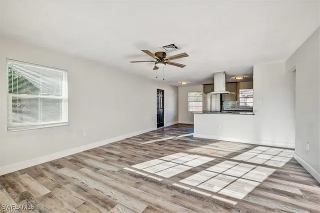 a view of a kitchen with a stove cabinets a ceiling fan and wooden floor