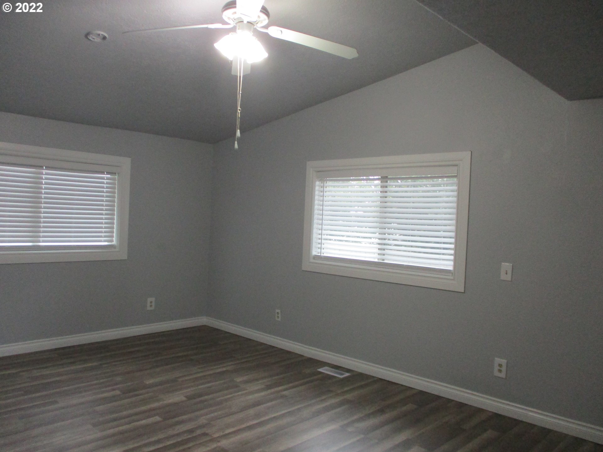 10038 South New Era Road, Unit 2 Canby, OR 97013 - Photo 5 of 20 an empty room with wooden floor chandelier fan and windows