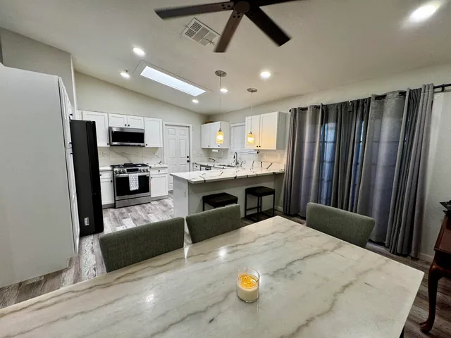 a kitchen with stainless steel appliances kitchen island granite countertop a refrigerator a stove top oven a sink with island and chairs