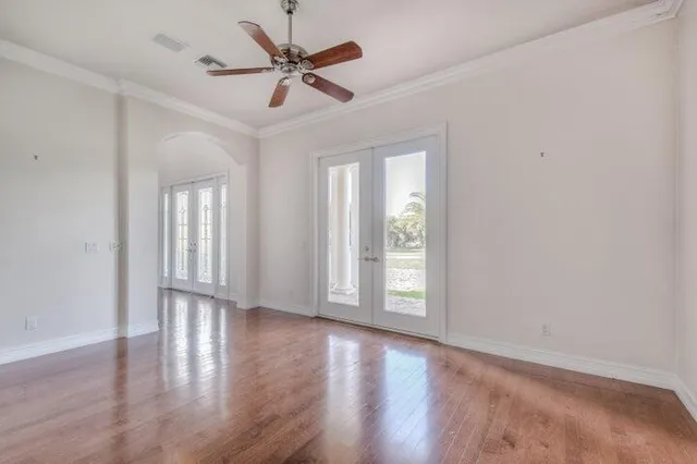 an empty room with wooden floor fan and windows