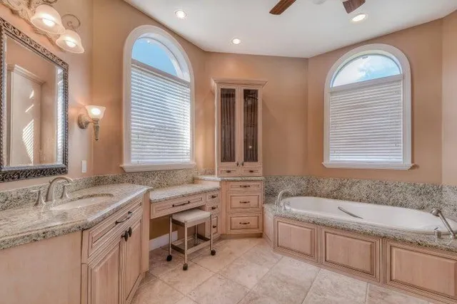 a spacious bathroom with sinks granite countertop tub a sink and a window