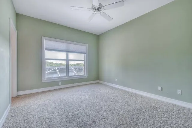 an empty room with a ceiling fan and window