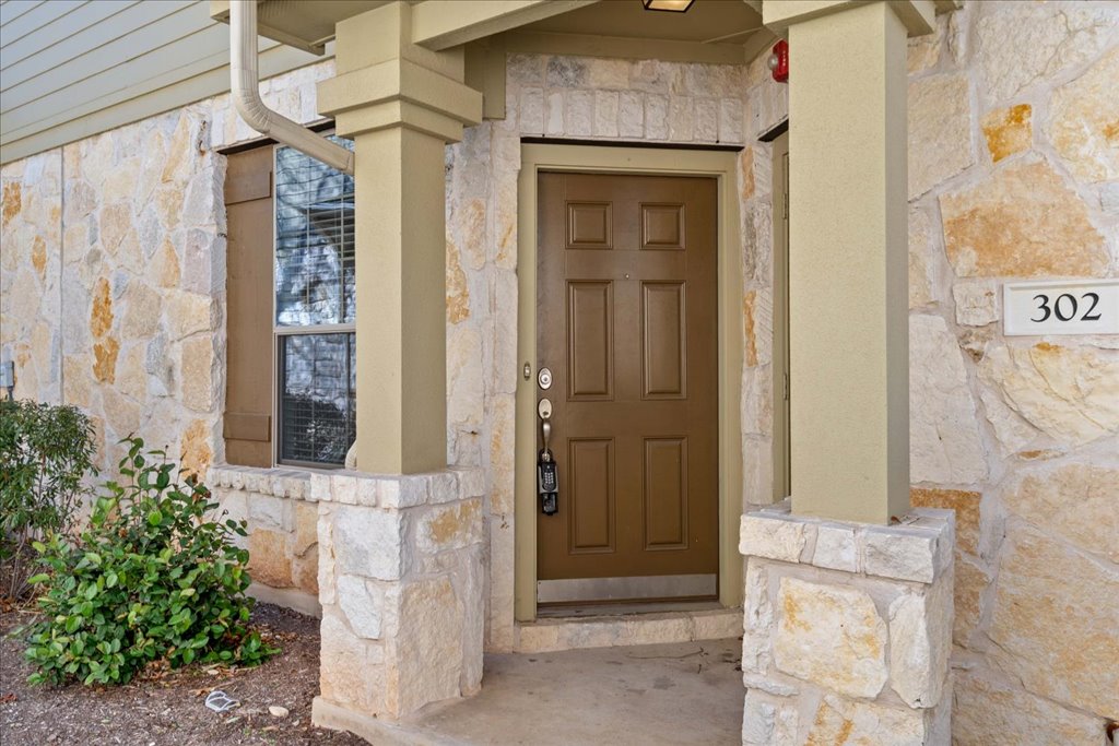 14815 Avery Ranch Boulevard, Unit 302 Austin, TX 78717 - Photo 1 of 30 The property features a stone exterior, a paneled entry door, and a decorative window with shutters