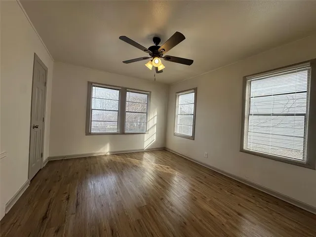 a view of an empty room with window and wooden floor