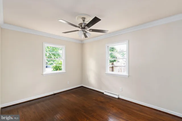 a view of an empty room with wooden floor and window