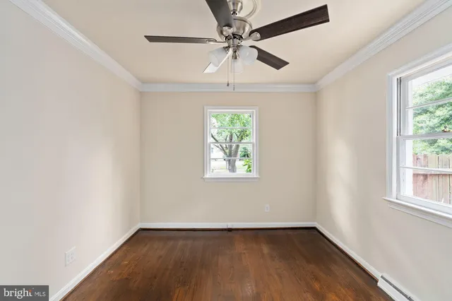 an empty room with wooden floor chandelier fan and windows