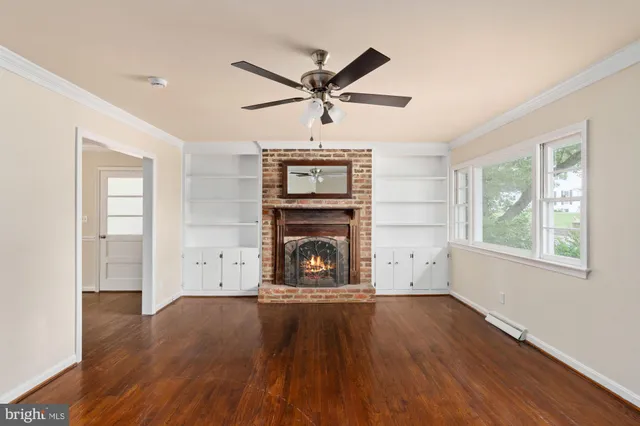 an empty room with windows fireplace and wooden floor