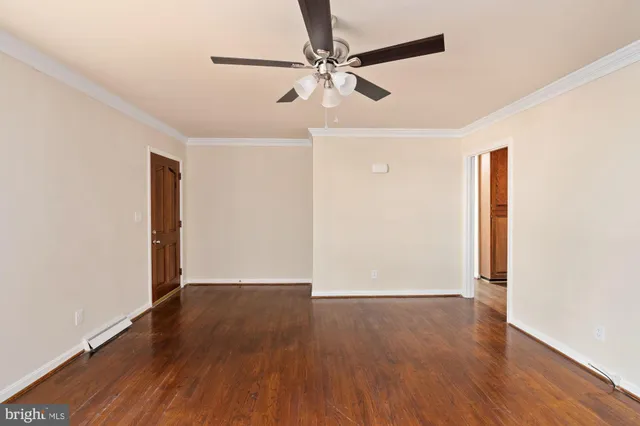 an empty room with wooden floor and a ceiling fan