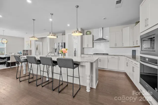 a kitchen with stainless steel appliances kitchen island granite countertop a dining table chairs and sink