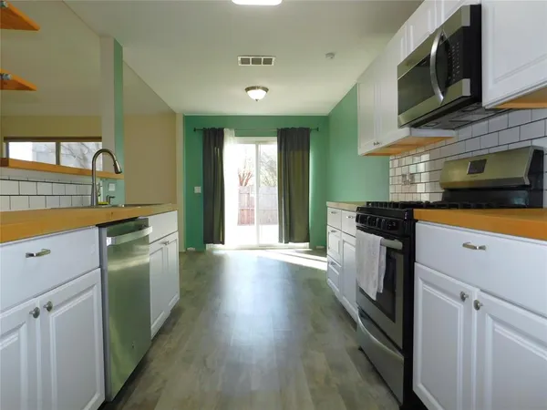 a kitchen with granite countertop a stove top oven a sink dishwasher and a refrigerator with wooden floor