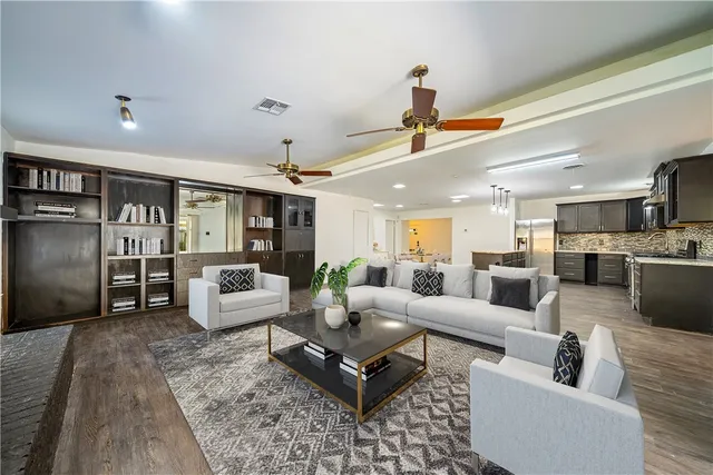 a living room with furniture kitchen view and a chandelier