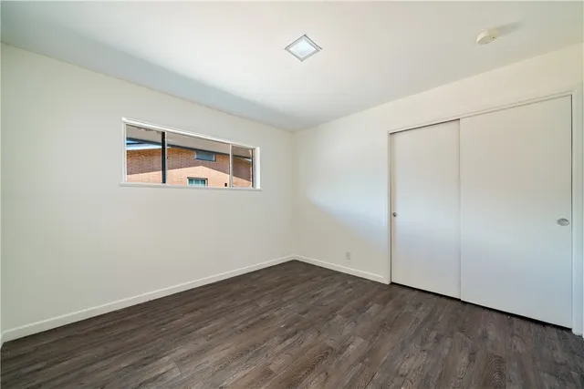an empty room with wooden floor and window