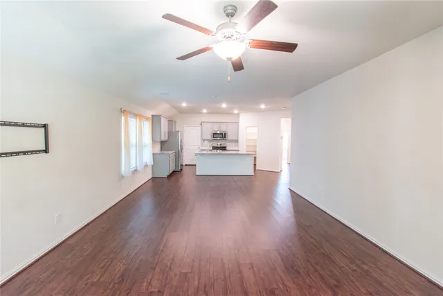 a view of an empty room with a kitchen and wooden floor