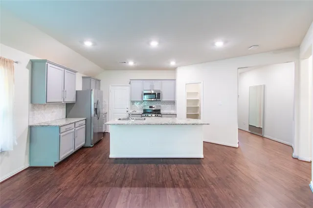 a kitchen with kitchen island wooden floors appliances and cabinets