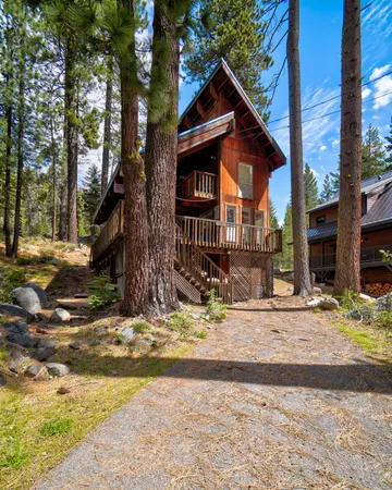 a view of the house with center tree and wooden fence