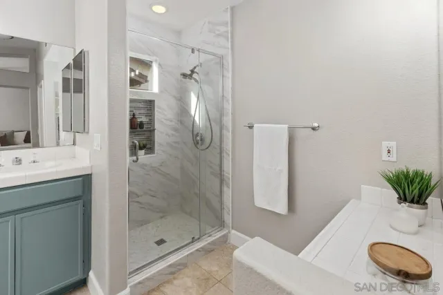 a bathroom with a granite countertop sink a mirror and shower