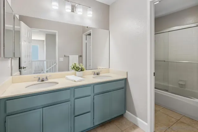 a bathroom with a granite countertop sink mirror and a bathtub
