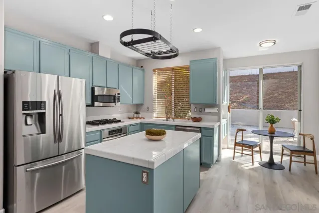 a kitchen with a refrigerator a stove a sink and a dining table with wooden floor