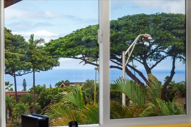 a view of patio with table and chairs under an umbrella with a small yard
