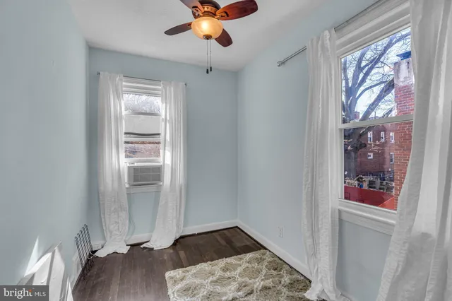 an empty room with wooden floor closet and windows