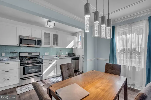 a kitchen with stainless steel appliances granite countertop a stove top oven a sink dishwasher a dining table and chairs with wooden floor