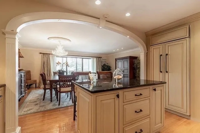a dining hall with stainless steel appliances granite countertop a stove and a view of living room