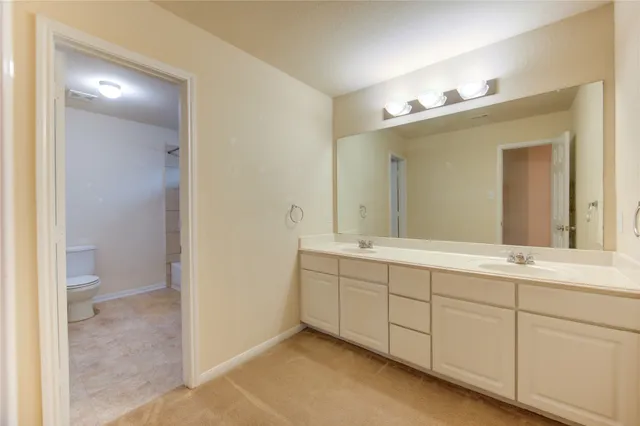 a spacious bathroom with a double vanity sink mirror and toilet