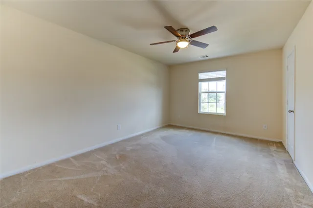 an empty room with a window and a fan