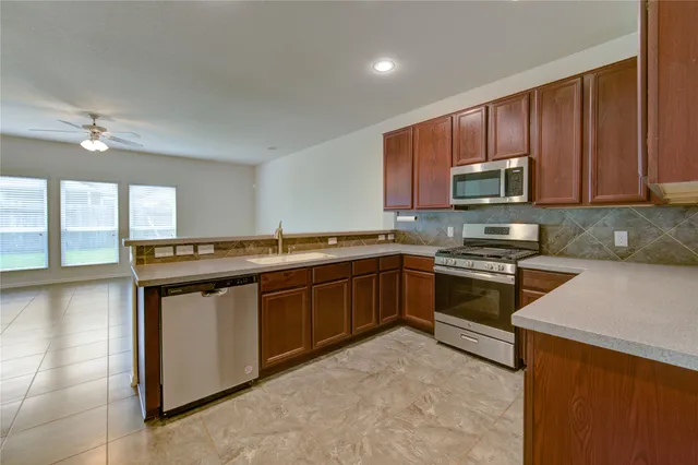 a kitchen with stainless steel appliances granite countertop a stove a sink and a microwave