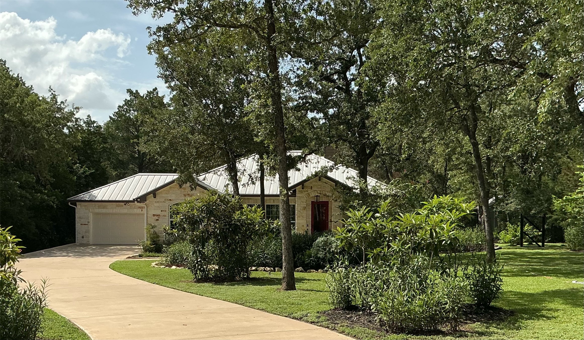 118 Loblolly Elgin, TX 78621 - Photo 3 of 31 A winding driveway leads to this charming stone home nestled amidst mature trees and lush landscaping.