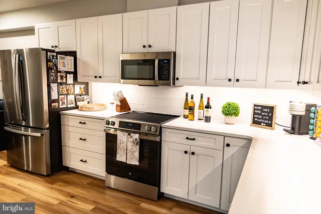 a kitchen with stainless steel appliances white cabinets and a refrigerator