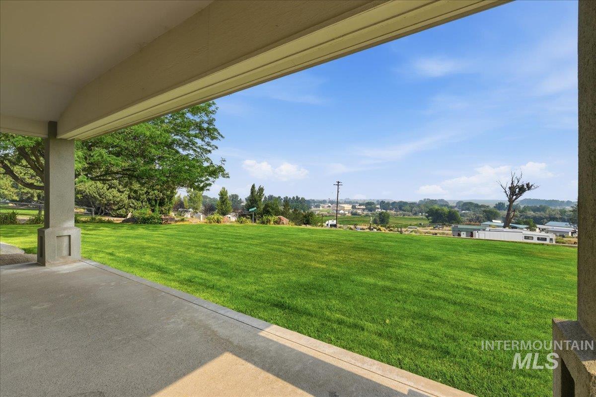 310 Frontage Road Grand View, ID 83624 - Photo 27 of 38 Covered concrete patio overlooking a sprawling green lawn with mature trees and distant landscape