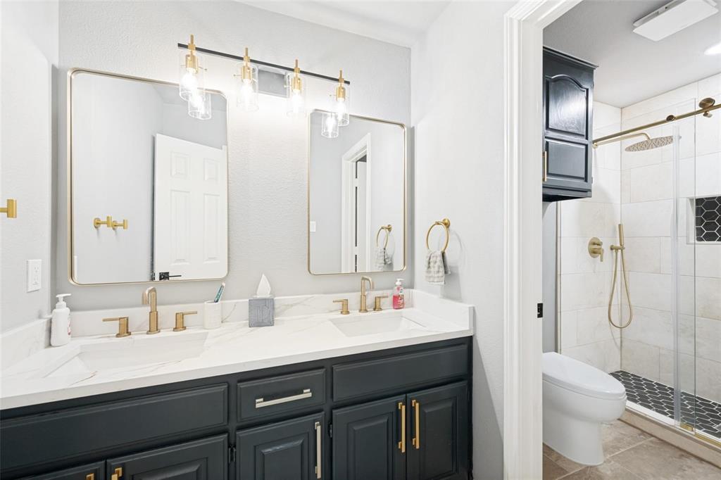 818 Riviera Drive Mansfield, TX 76063 - Photo 5 of 24 Bathroom featuring a dual vanity with white countertops, undermount sinks, and gold-finish fixtures
