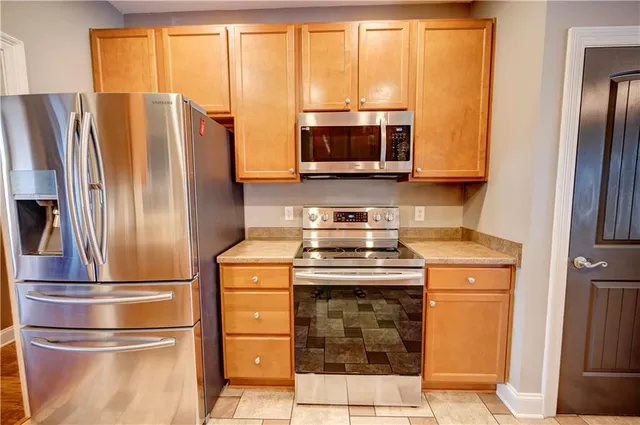 a kitchen with stainless steel appliances granite countertop a refrigerator and a stove top oven
