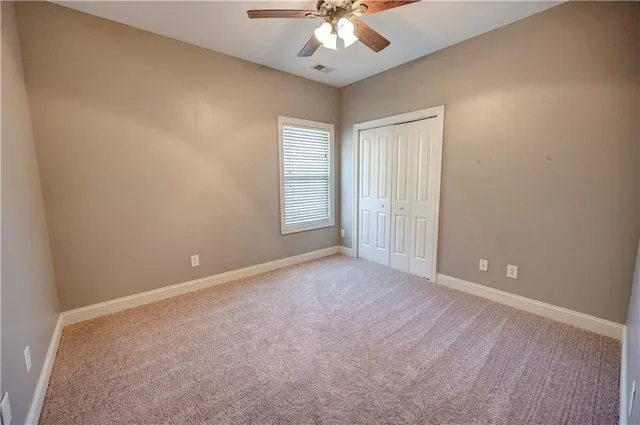 a view of an empty room with closet and a window
