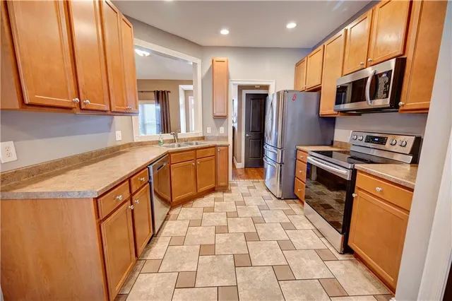 a kitchen with stainless steel appliances granite countertop a refrigerator a stove top oven and sink
