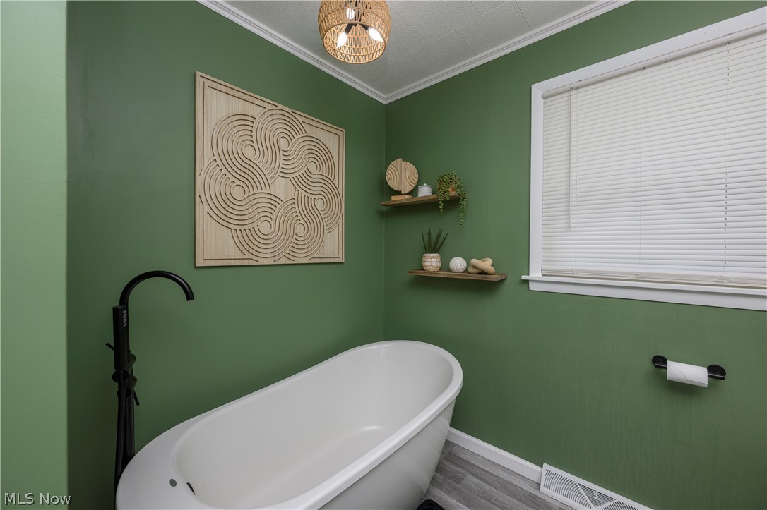 6105 Wolf Run Road Southeast Dennison, OH 44621 - Photo 24 of 35 Bathroom featuring a freestanding tub with a matte black floor-mounted faucet, wood-finish flooring, and a window with horizontal blinds